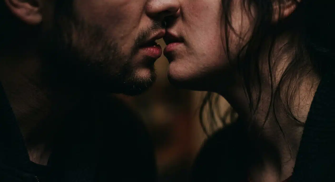 A close-up of two people about to kiss, featuring only their subtle expressions and dim lighting, creating an intimate and romantic atmosphere
