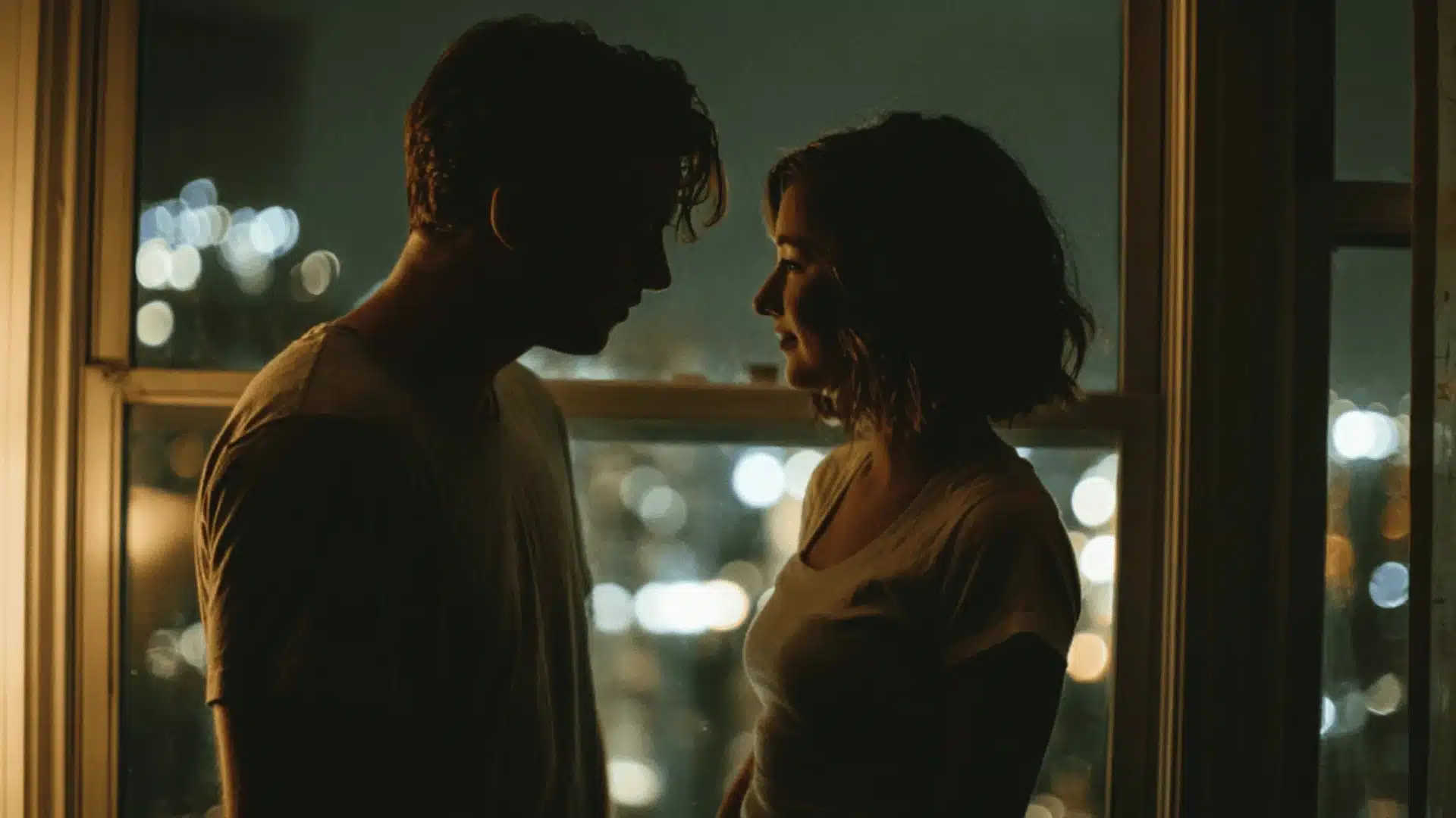 A silhouetted man and woman face each other by a window at night with blurry city lights glowing in the dark background