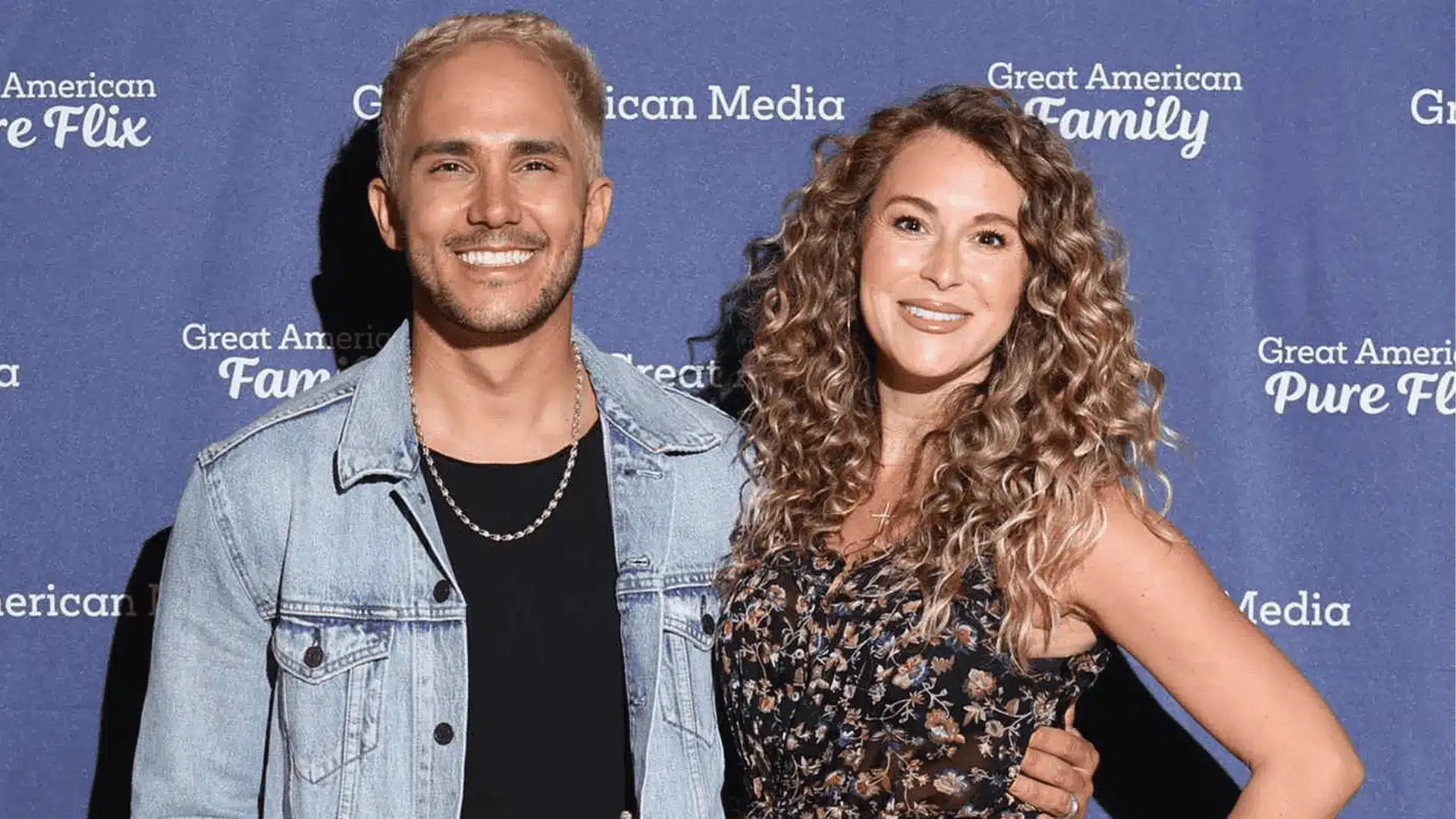 Alexa and Carlos PenaVega pose together at an event, showcasing their fashionable outfits and warm, friendly demeanor