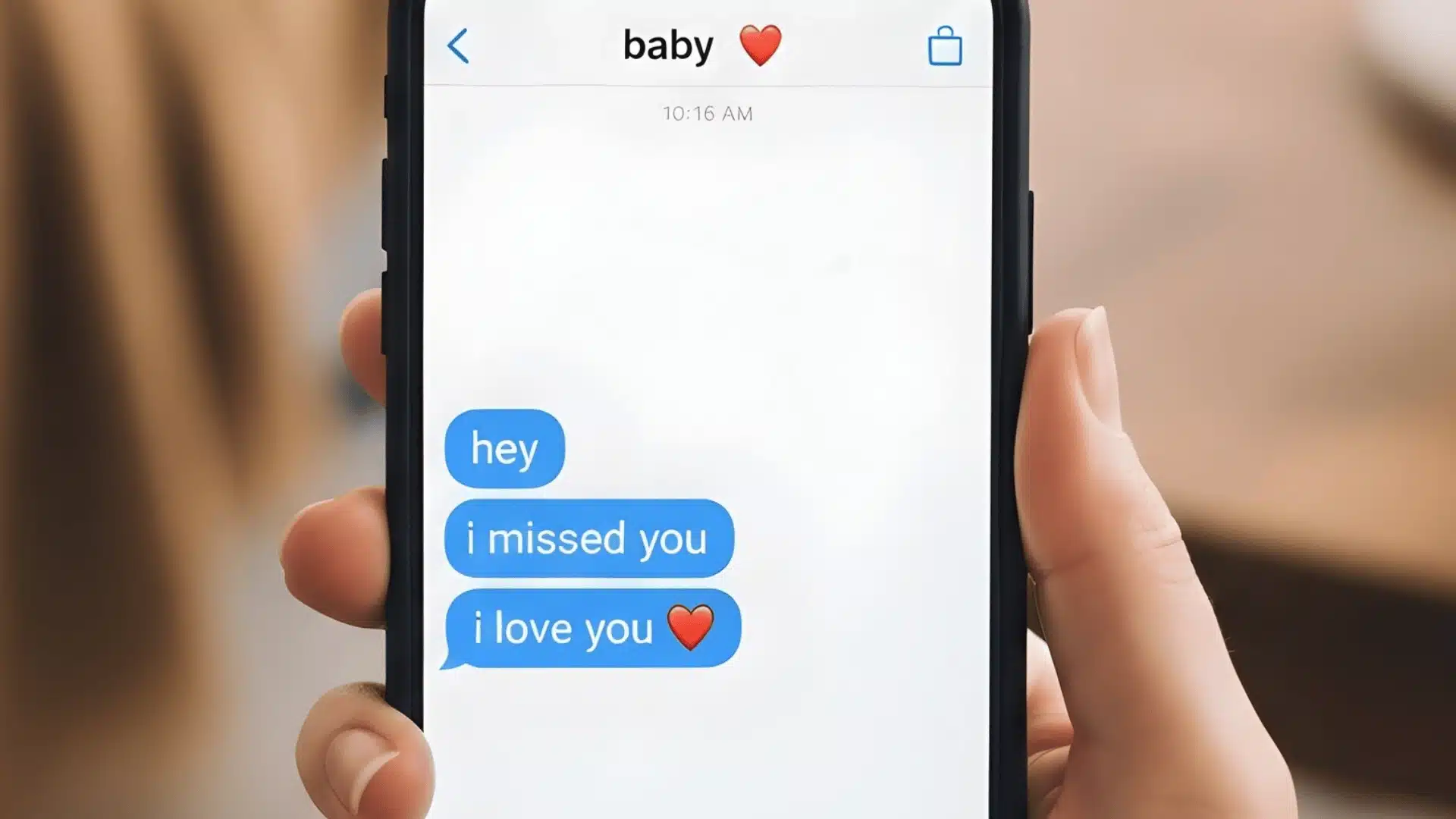 Close up of a hand holding a smartphone displaying text messages to baby that read hey, i missed you, and i love you