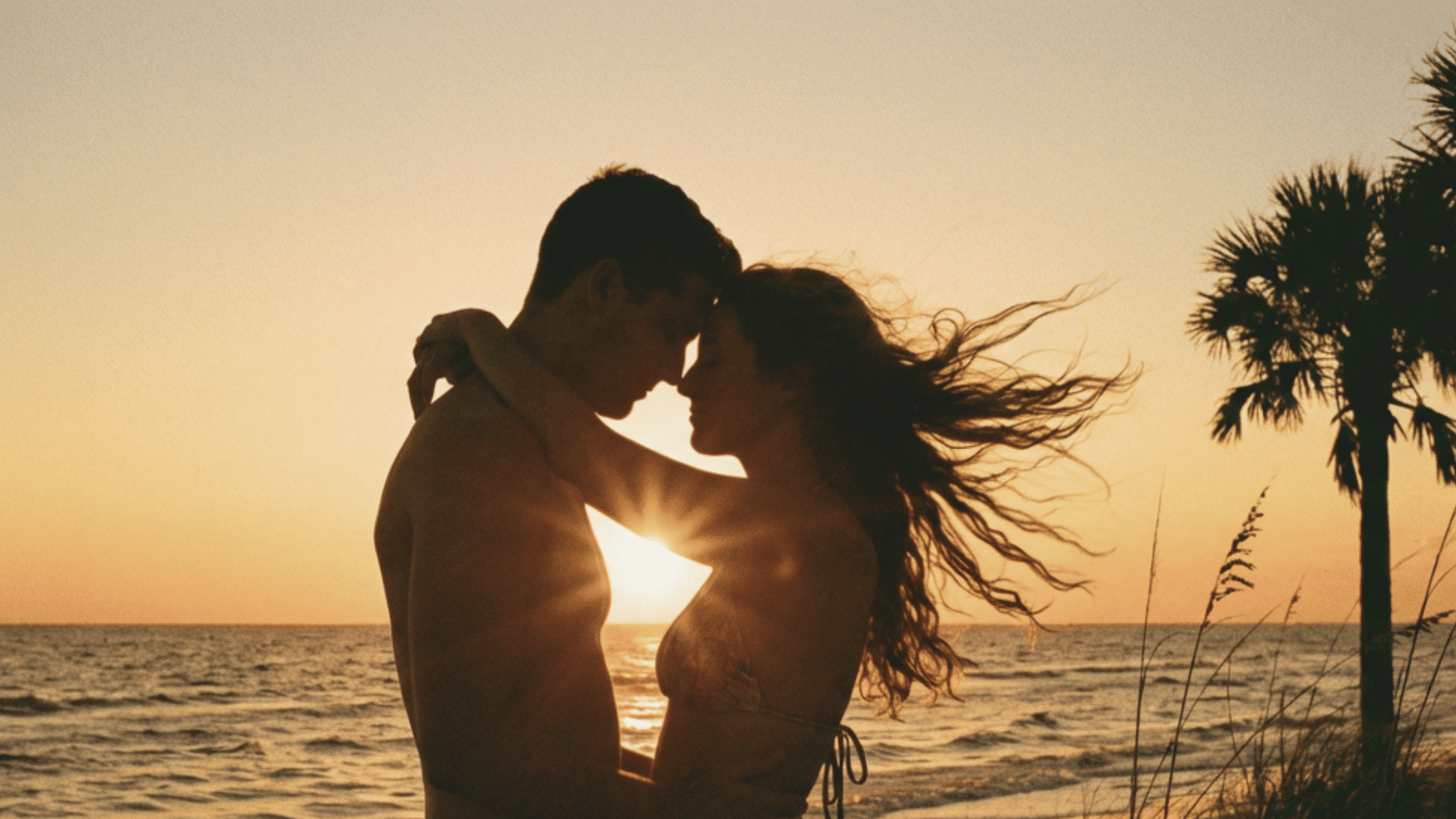 Couple embracing on a beach at sunset, showing love and deep romantic intimacy