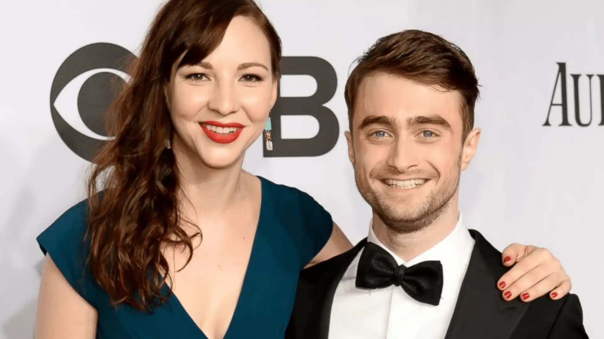 Daniel Radcliffe and Erin Darke posing together at an event, sharing smiles and showcasing their elegant presence