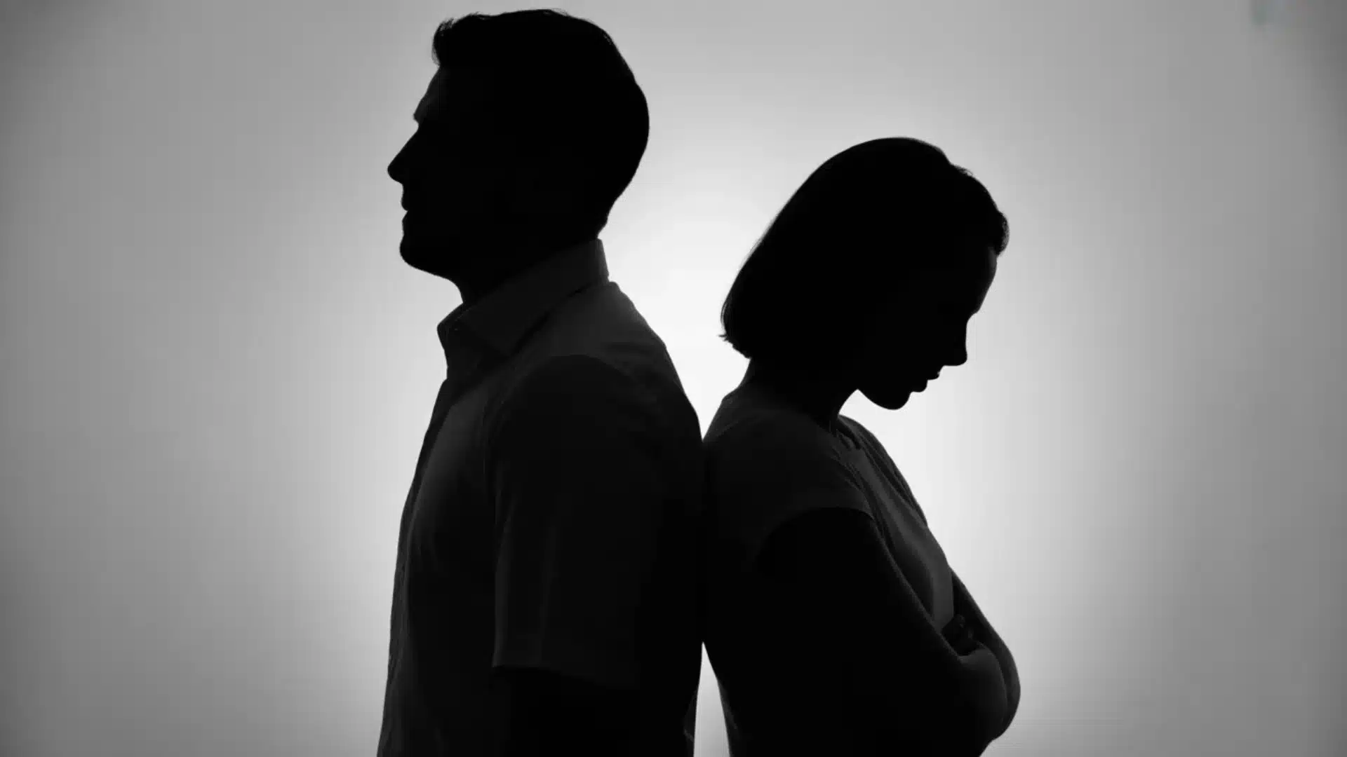 Silhouette of couple standing back to back, showing distance and emotional disconnect