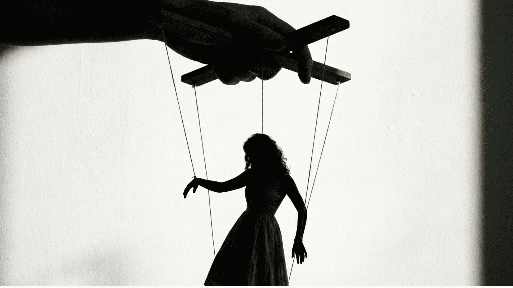 Silhouette of woman as puppet with strings controlled by hand, symbolizing control (1)
