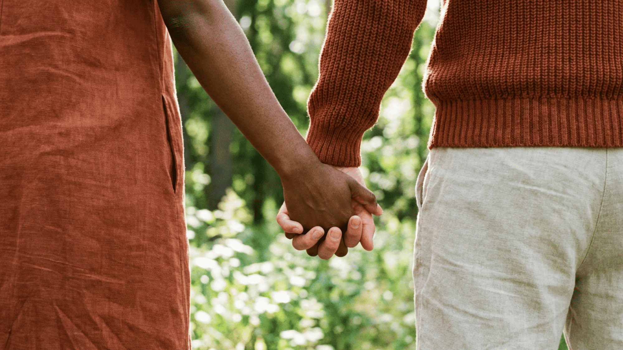 Two people holding hands outdoors, showing closeness and emotional connection.