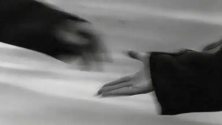 A monochrome photo depicting two hands reaching out, illustrating a gesture of support and human connection