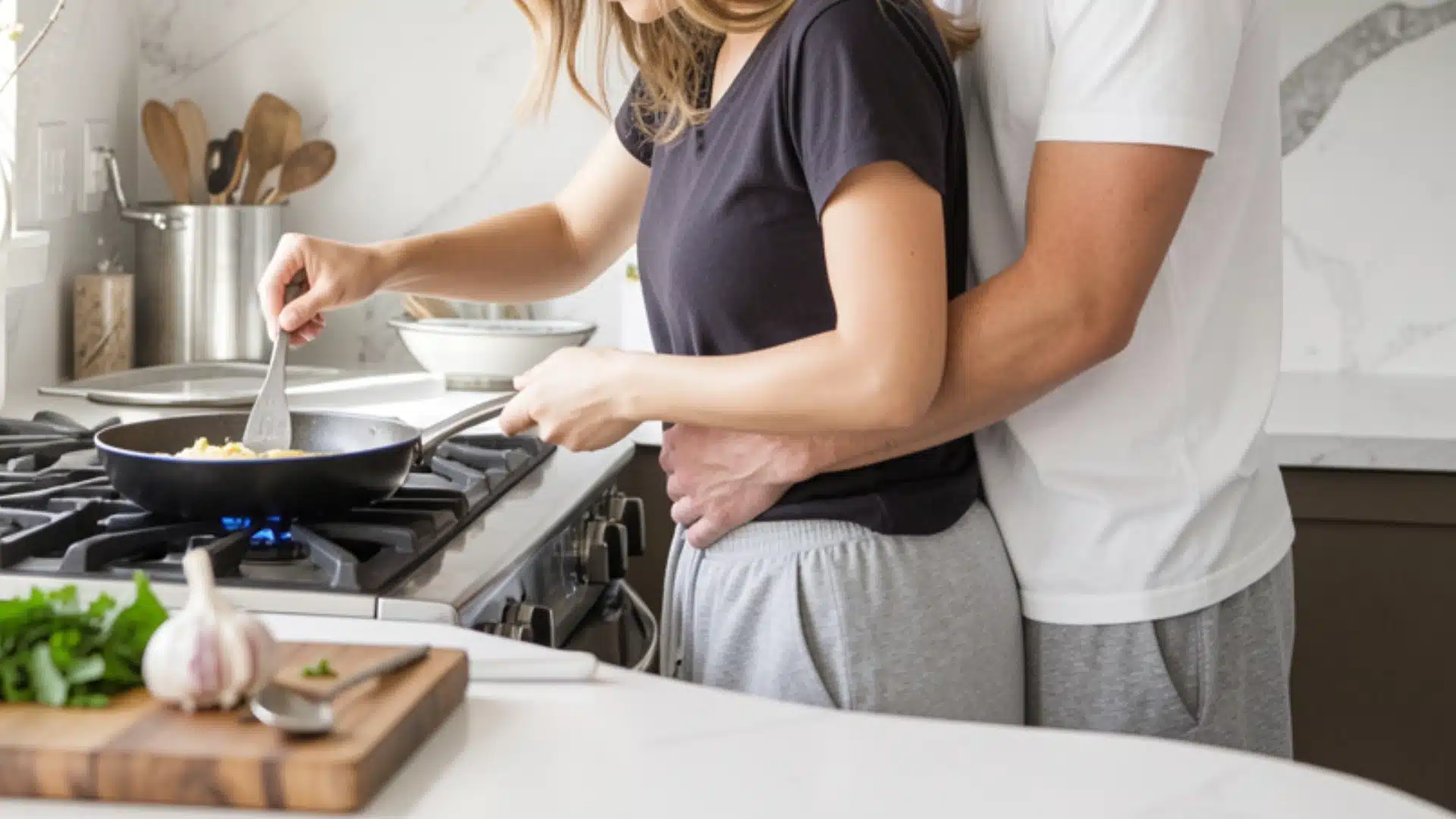 A couple cooks in a kitchen, engaged in meal preparation with pots, pans, and fresh ingredients on the counter.