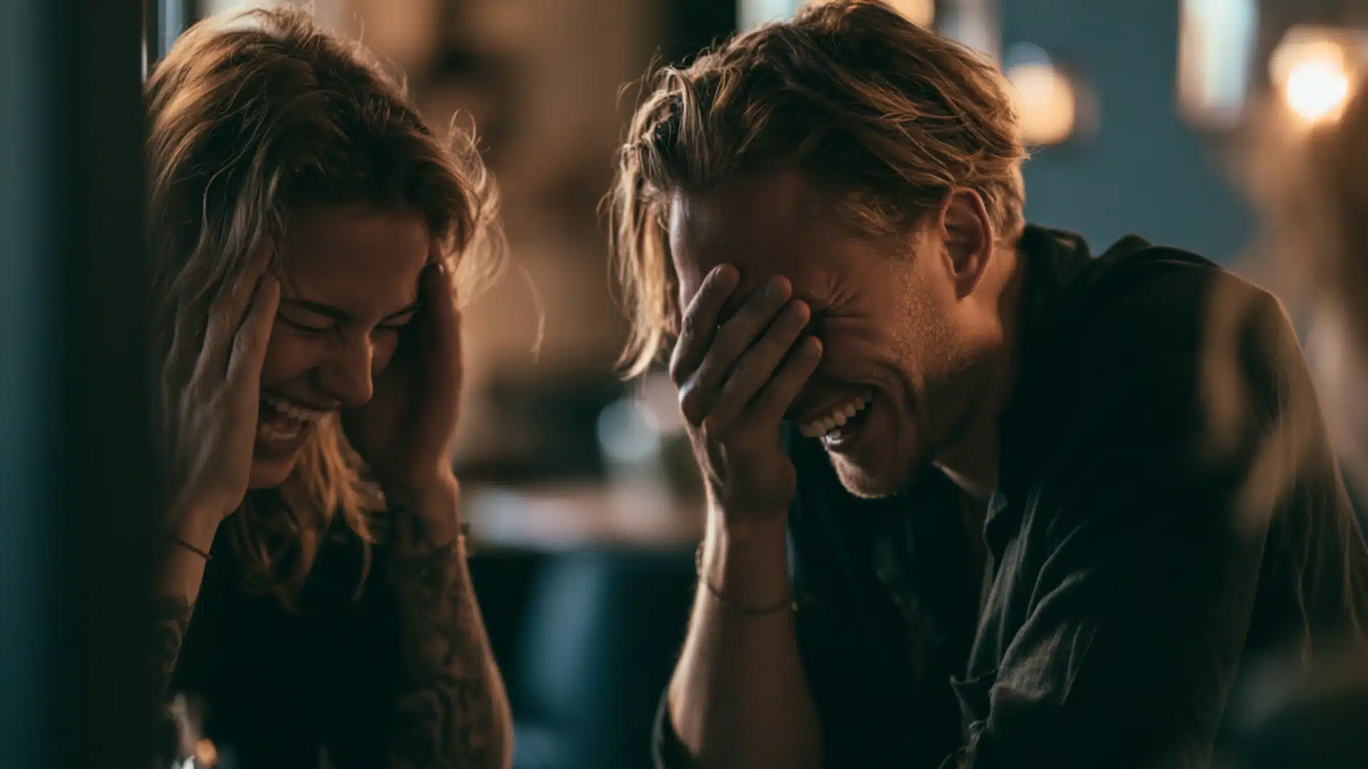 A couple enjoys a lighthearted conversation, both laughing at a restaurant table