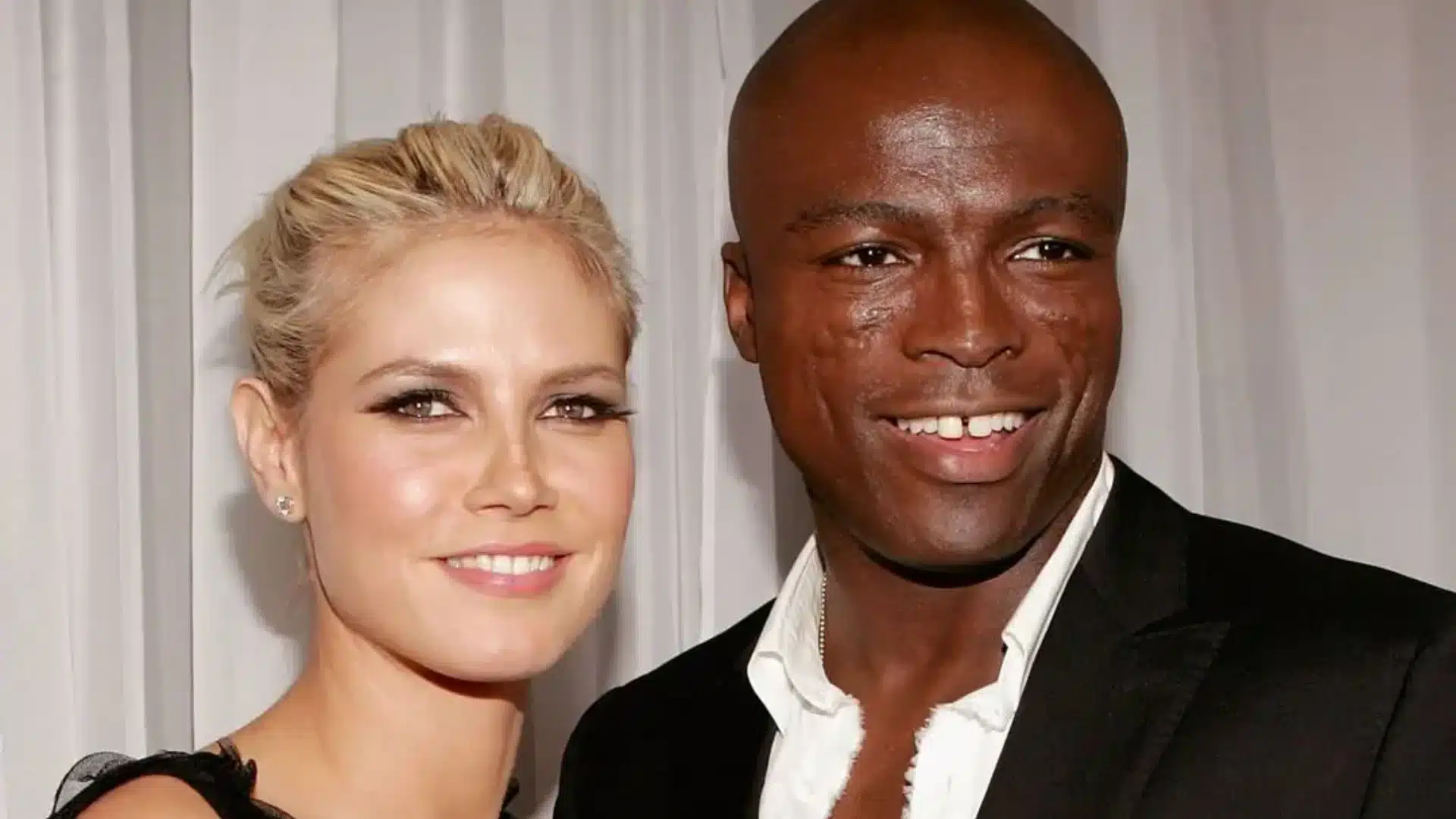 Heidi Klum and Seal smiling together at an event against a light background