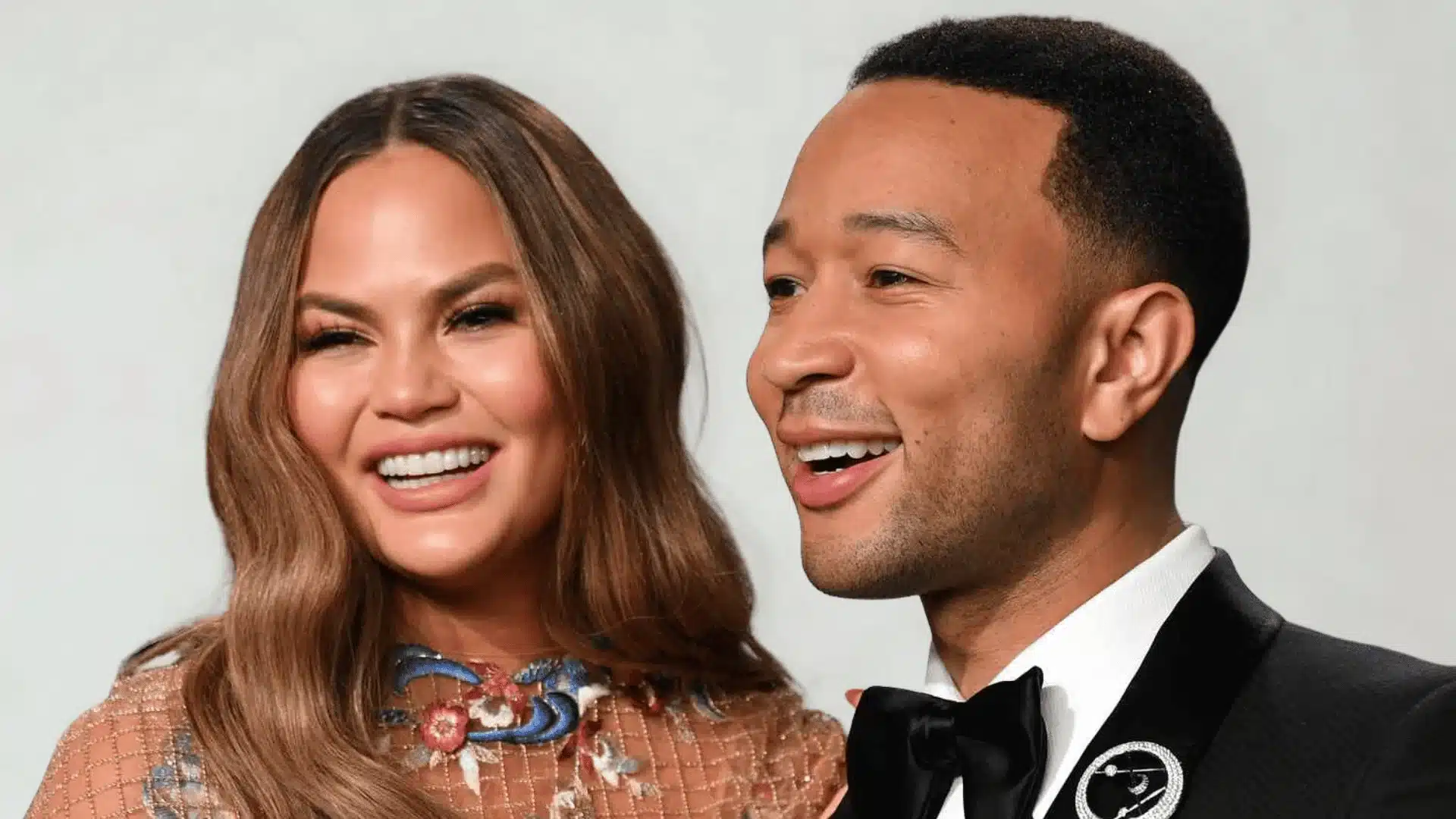 Chrissy Teigen and John Legend smile close together in formal attire.
