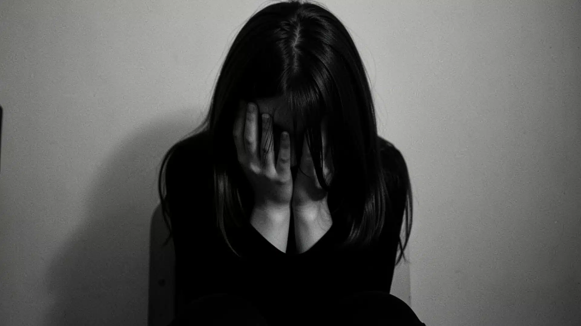 A woman in a chair, hands on her face, conveys a sense of deep thought or emotional struggle.