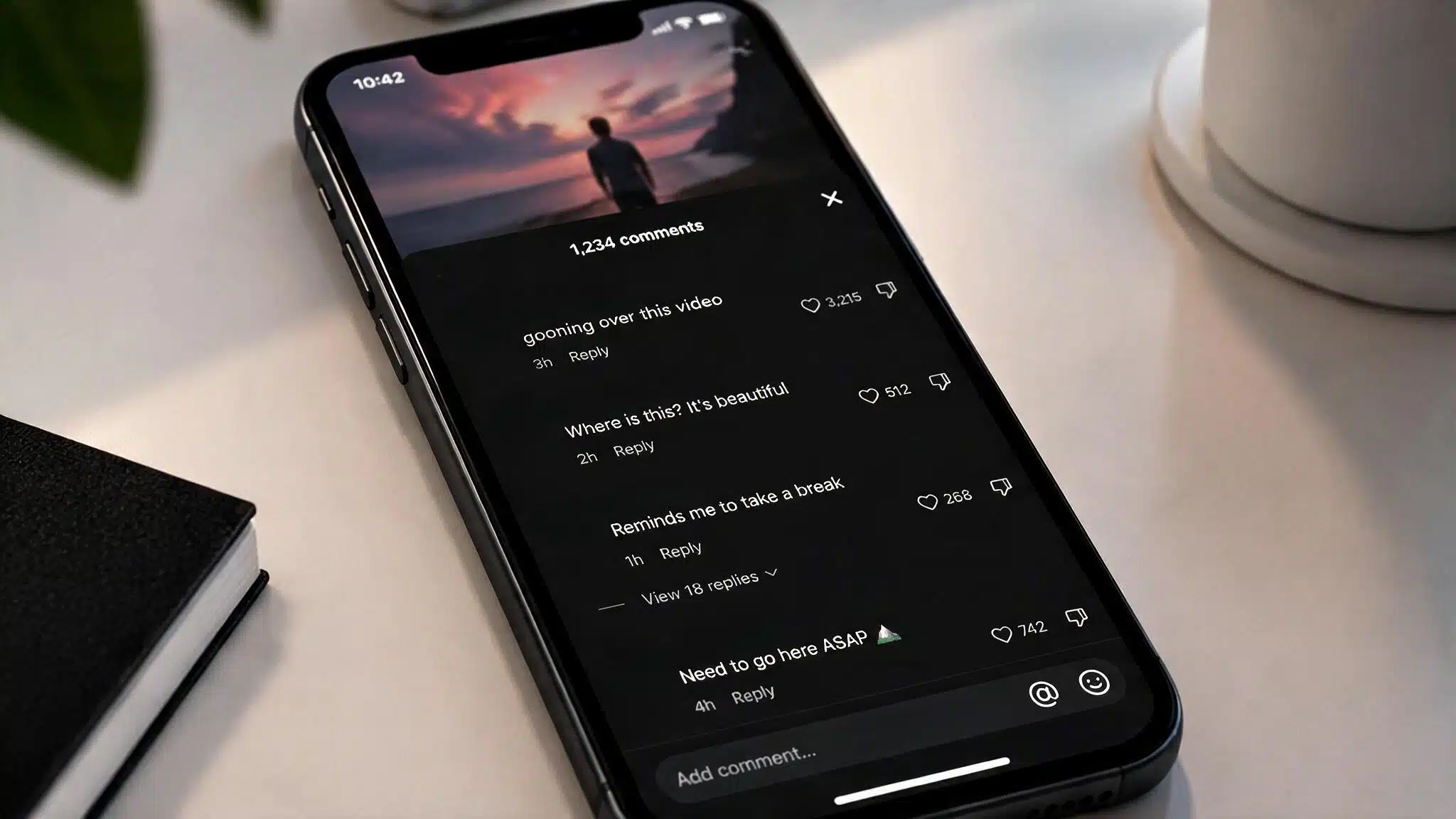Smartphone displaying a social media comment section with humorous comments about repeatedly watching a video, placed on a minimalist desk.